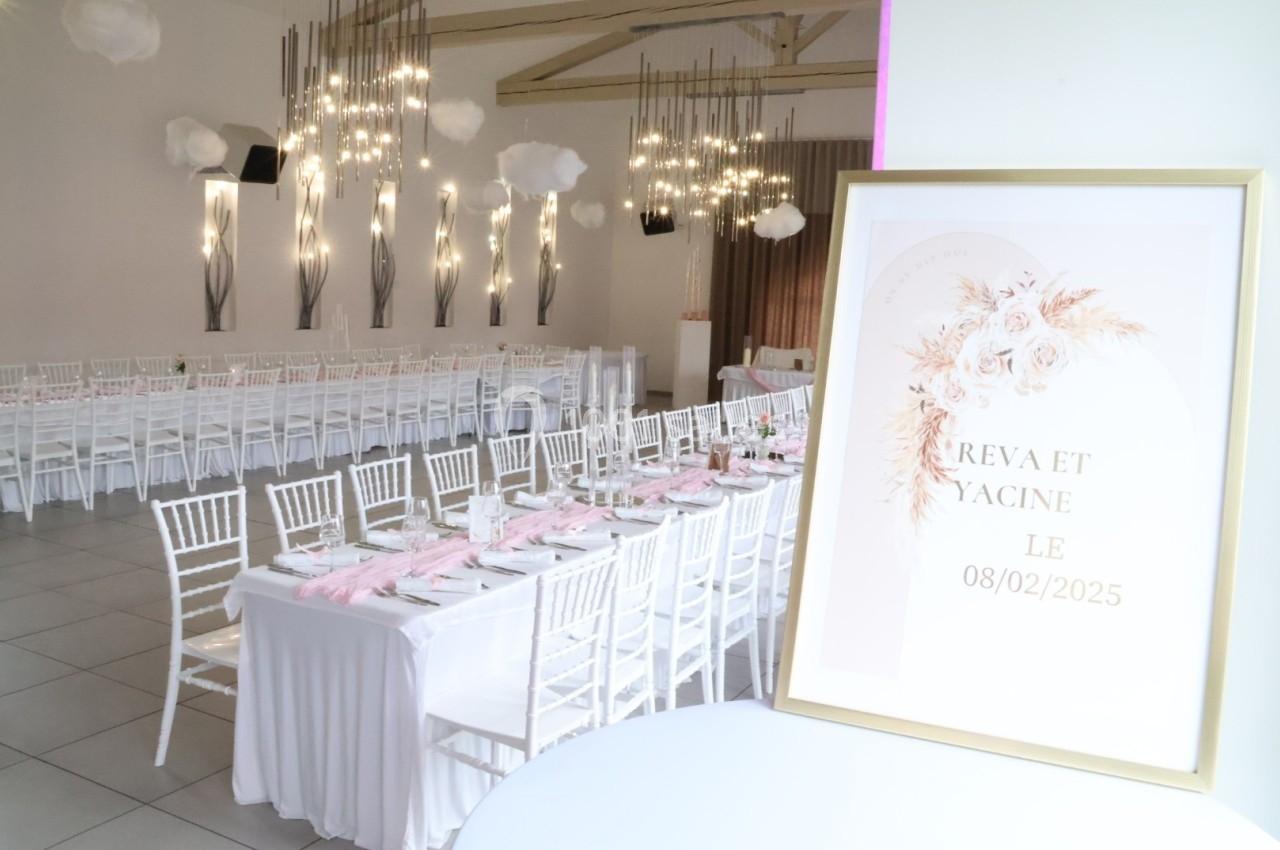 Salle de réception décorée avec des tables alignées, chaises blanches et un panneau annonçant un événement le 08/02/2025.