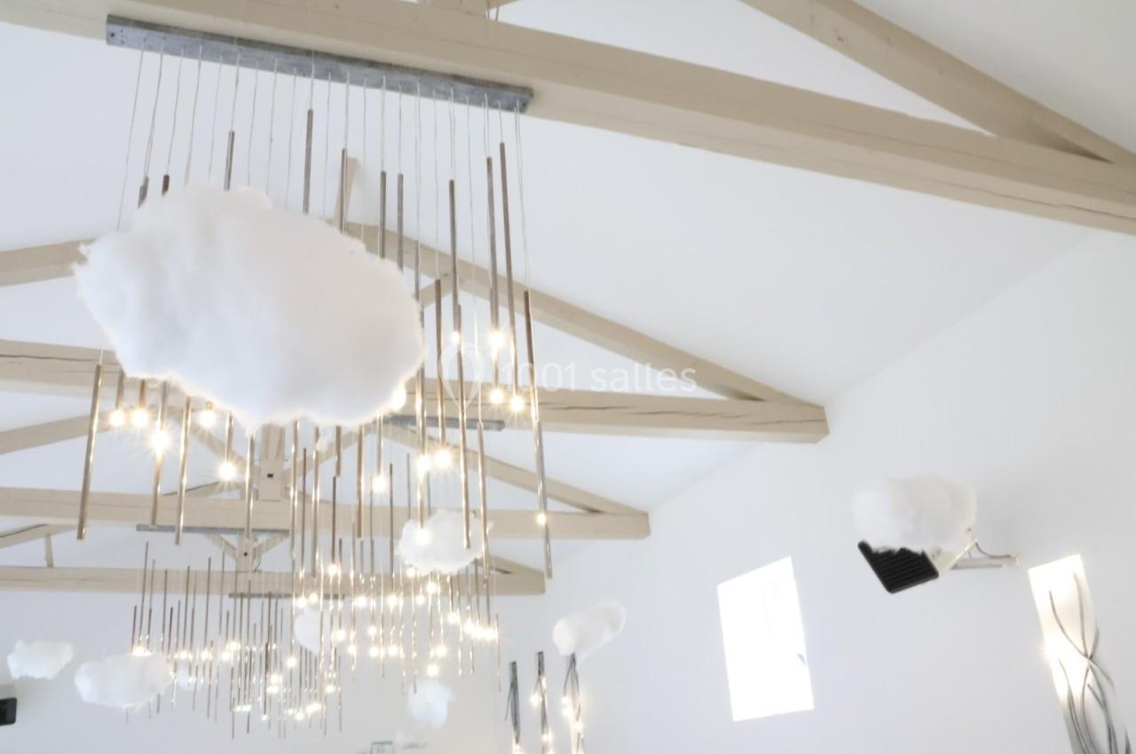 Suspension lumineuse moderne avec des nuages décoratifs blancs accrochés à des tiges métalliques dans une pièce lumineuse.