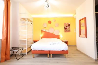 Chambre d'hôtel moderne avec lit double, murs verts, salle de bain attenante et mobilier contemporain.