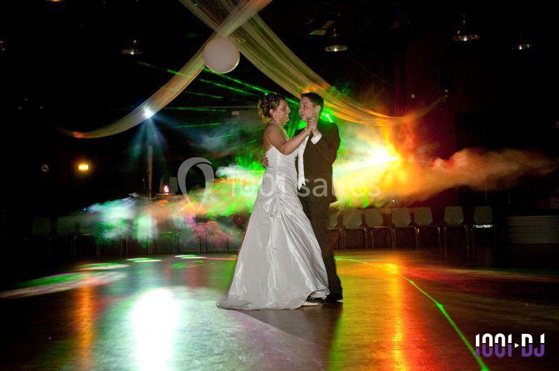 Un couple danse dans une salle éclairée par des lumières colorées et des effets de fumée.
