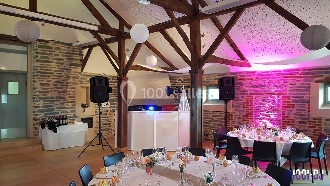 Salle de réception décorée avec des tables dressées, éclairage coloré et équipement audio installé.