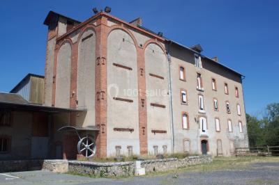Salle de bain publique avec lavabos en inox, carrelage bleu et blanc, et portes de cabines fermées.