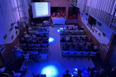 Salle de bain publique avec lavabos en inox, carrelage bleu et blanc, et portes de cabines fermées.