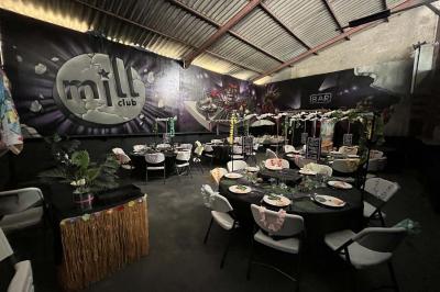 Salle de bain publique avec lavabos en inox, carrelage bleu et blanc, et portes de cabines fermées.
