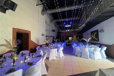 Salle de bain publique avec lavabos en inox, carrelage bleu et blanc, et portes de cabines fermées.