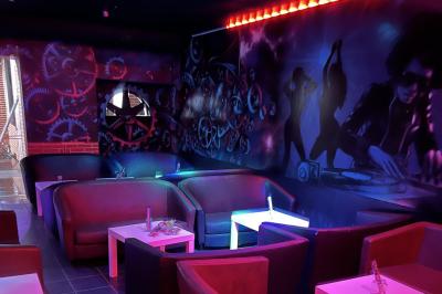 Salle de bain publique avec lavabos en inox, carrelage bleu et blanc, et portes de cabines fermées.