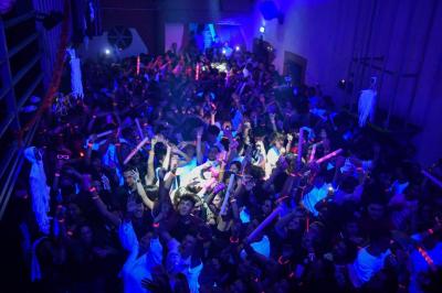 Salle de bain publique avec lavabos en inox, carrelage bleu et blanc, et portes de cabines fermées.
