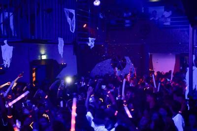 Salle de bain publique avec lavabos en inox, carrelage bleu et blanc, et portes de cabines fermées.