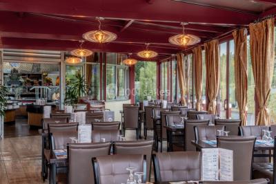 Salle de restaurant avec buffet circulaire, décorations lumineuses et grandes baies vitrées donnant sur un espace vert.