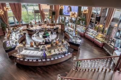 Salle de restaurant avec buffet circulaire, décorations lumineuses et grandes baies vitrées donnant sur un espace vert.
