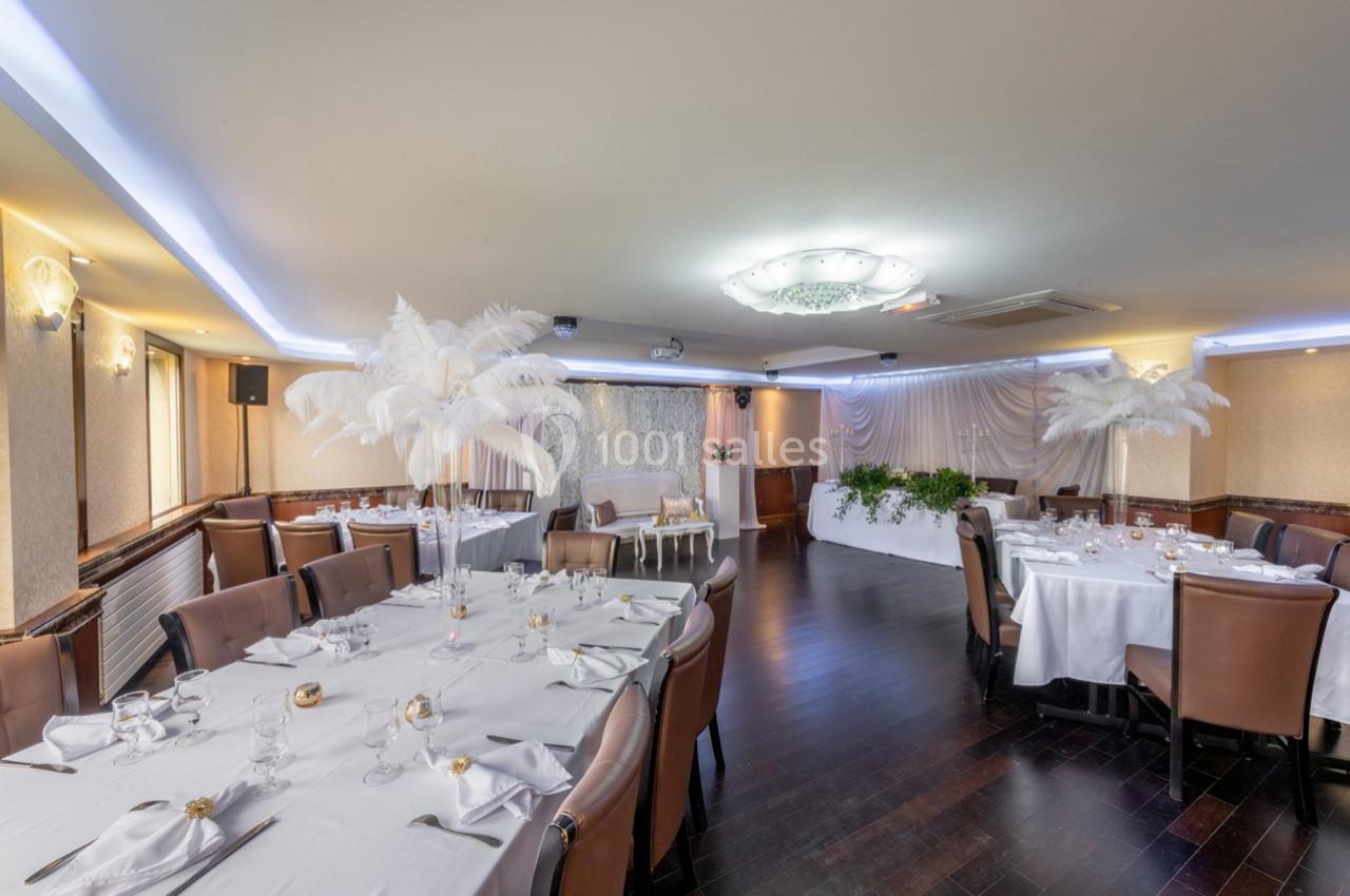 Salle de réception élégante avec tables dressées, décorations blanches et éclairage tamisé.