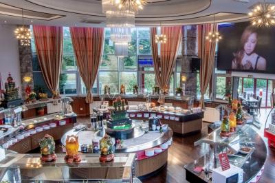 Salle de restaurant avec buffet circulaire, décorations lumineuses et grandes baies vitrées donnant sur un espace vert.