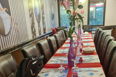 Salle de restaurant avec buffet circulaire, décorations lumineuses et grandes baies vitrées donnant sur un espace vert.