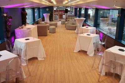 Espace extérieur d'un bateau avec fauteuils modernes, table basse, bouée de sauvetage et vue sur une rivière et un pont.