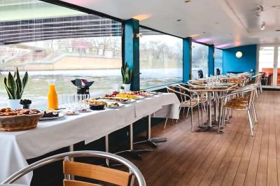 Espace extérieur d'un bateau avec fauteuils modernes, table basse, bouée de sauvetage et vue sur une rivière et un pont.