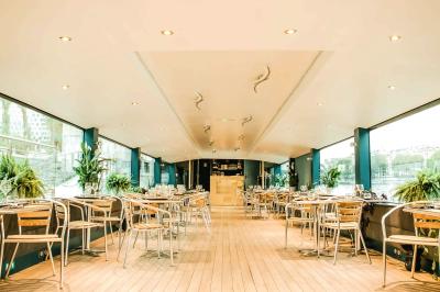 Espace extérieur d'un bateau avec fauteuils modernes, table basse, bouée de sauvetage et vue sur une rivière et un pont.