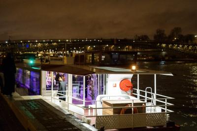 Espace extérieur d'un bateau avec fauteuils modernes, table basse, bouée de sauvetage et vue sur une rivière et un pont.