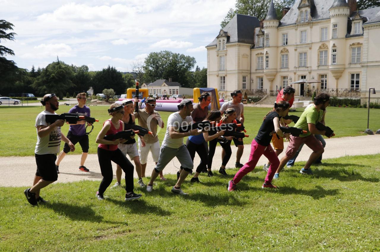 Un groupe de personnes participe à une activité de tir en plein air devant un château.