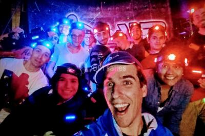 Flammes vives s'élevant d'un feu de bois sous une grille métallique, entourées de pierres sombres.