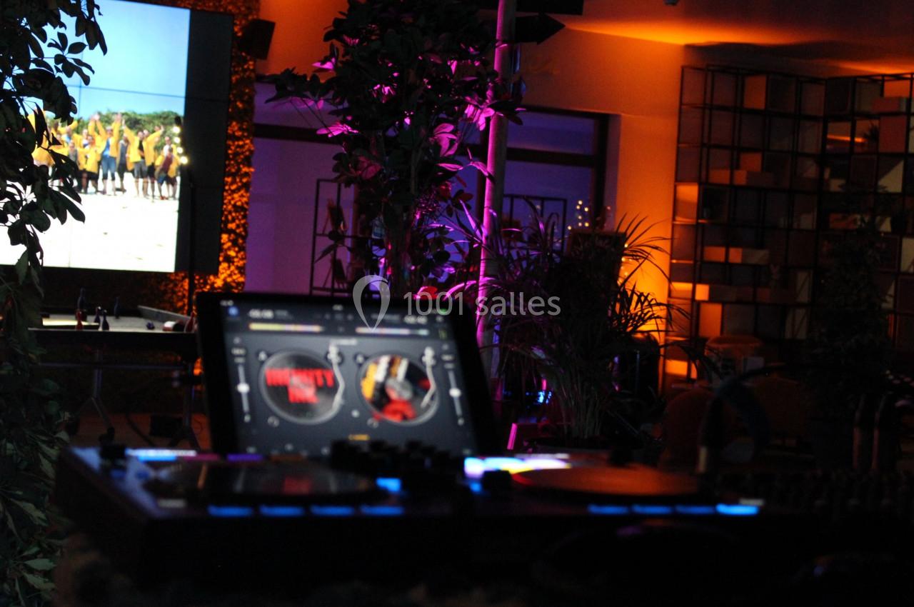 Poste de DJ avec platines éclairées au premier plan, écran et décor lumineux en arrière-plan.