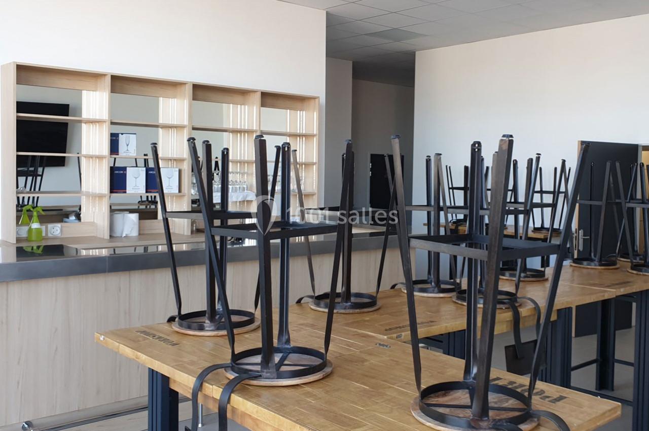 Chaises retournées sur des tables en bois dans une salle de classe ou de formation vide avec des étagères en arrière-plan.