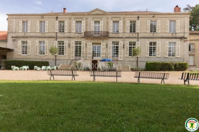 Un hélicoptère posé sur une pelouse, entouré d'arbres et de bâtiments en arrière-plan.