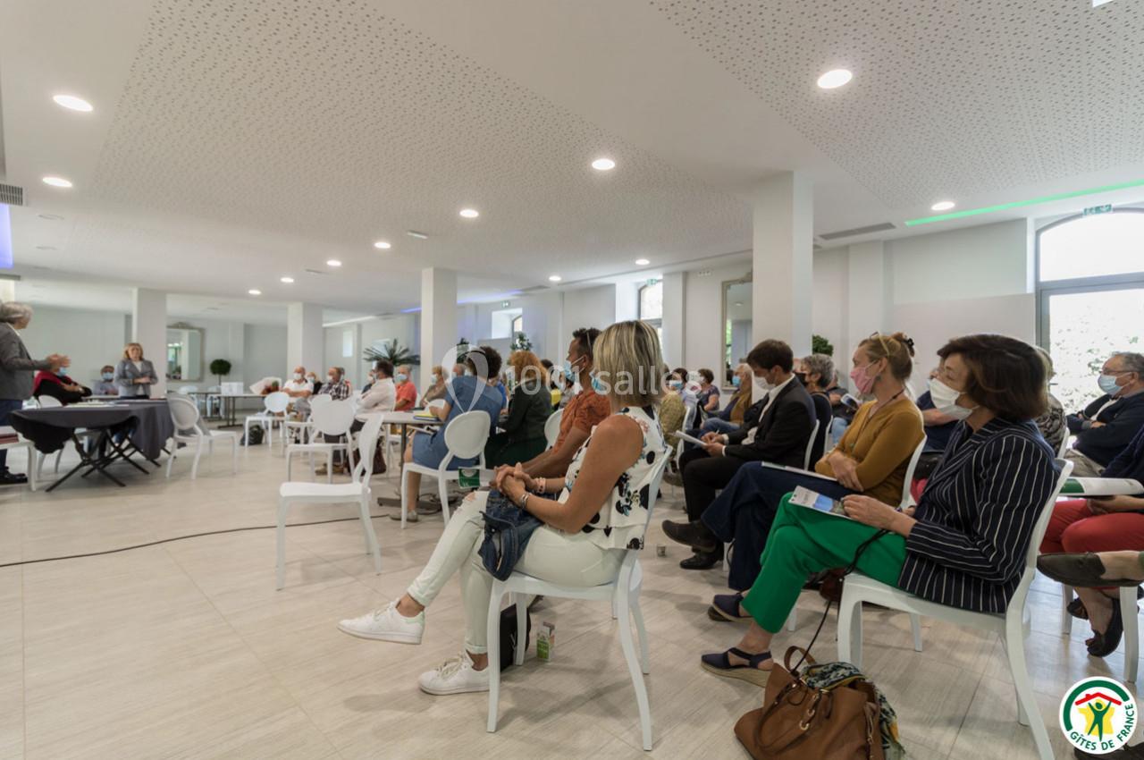 Personnes assises dans une salle de conférence lumineuse, écoutant une présentation.