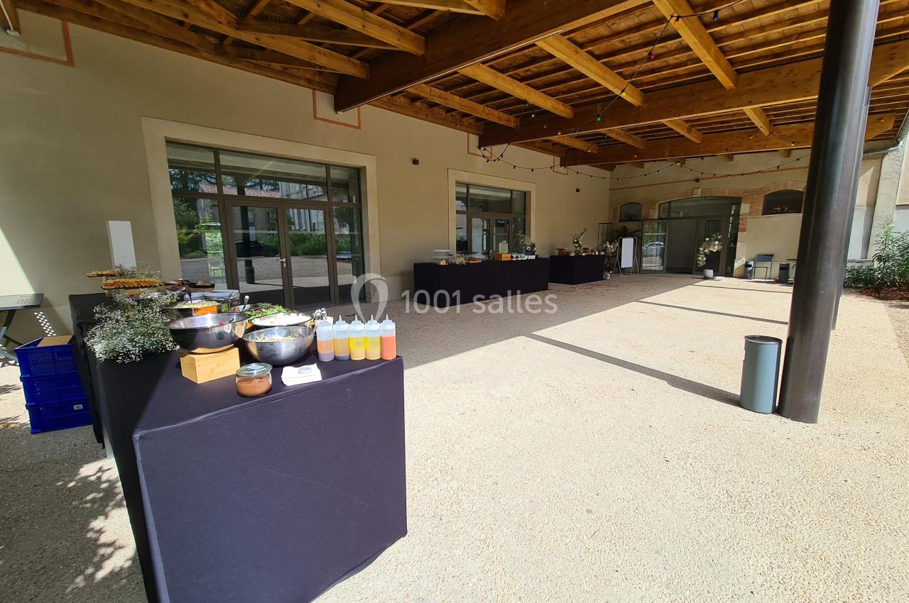 Tables de buffet dressées sous un auvent en bois, avec divers plats et condiments disposés sur des nappes noires.