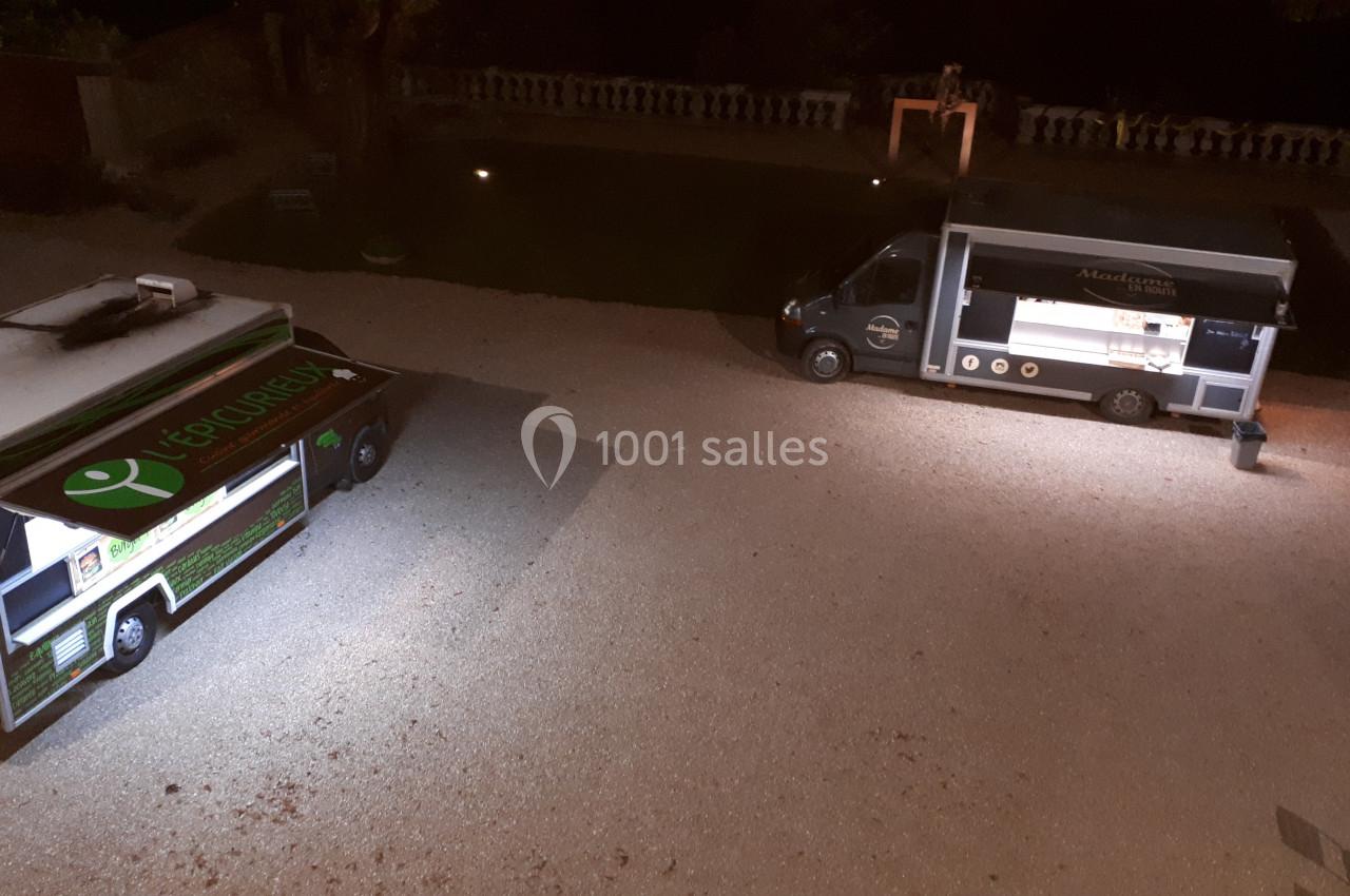 Deux food trucks stationnés de nuit sur un sol gravillonné, éclairés par leurs propres lumières.