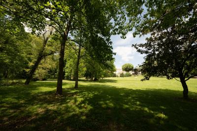 Un hélicoptère posé sur une pelouse, entouré d'arbres et de bâtiments en arrière-plan.