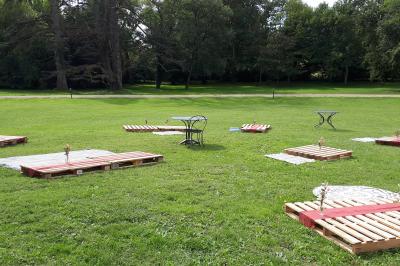 Un hélicoptère posé sur une pelouse, entouré d'arbres et de bâtiments en arrière-plan.