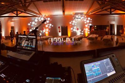 Installation de matériel de sonorisation et d'éclairage sous une tente, avec une table de mixage et des projecteurs.