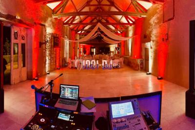 Installation de matériel de sonorisation et d'éclairage sous une tente, avec une table de mixage et des projecteurs.