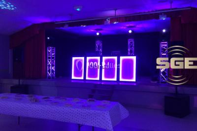 Façade en pierre éclairée par des lumières violettes, avec une porte voûtée et un sol en dalles.