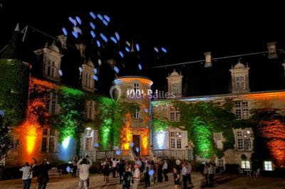 Façade en pierre éclairée par des lumières violettes, avec une porte voûtée et un sol en dalles.