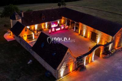 Façade en pierre éclairée par des lumières violettes, avec une porte voûtée et un sol en dalles.