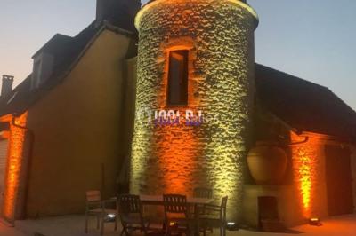 Façade en pierre éclairée par des lumières violettes, avec une porte voûtée et un sol en dalles.