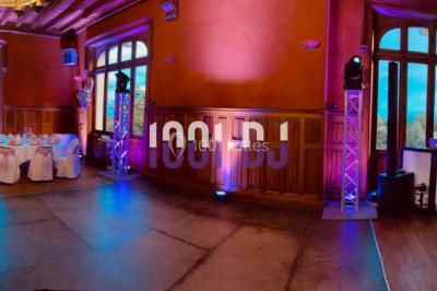 Façade en pierre éclairée par des lumières violettes, avec une porte voûtée et un sol en dalles.