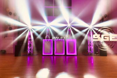 Façade en pierre éclairée par des lumières violettes, avec une porte voûtée et un sol en dalles.