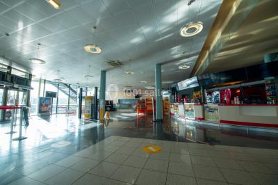 Façade vitrée d'un cinéma moderne sous un ciel bleu, avec trottoir et bâtiments en arrière-plan.