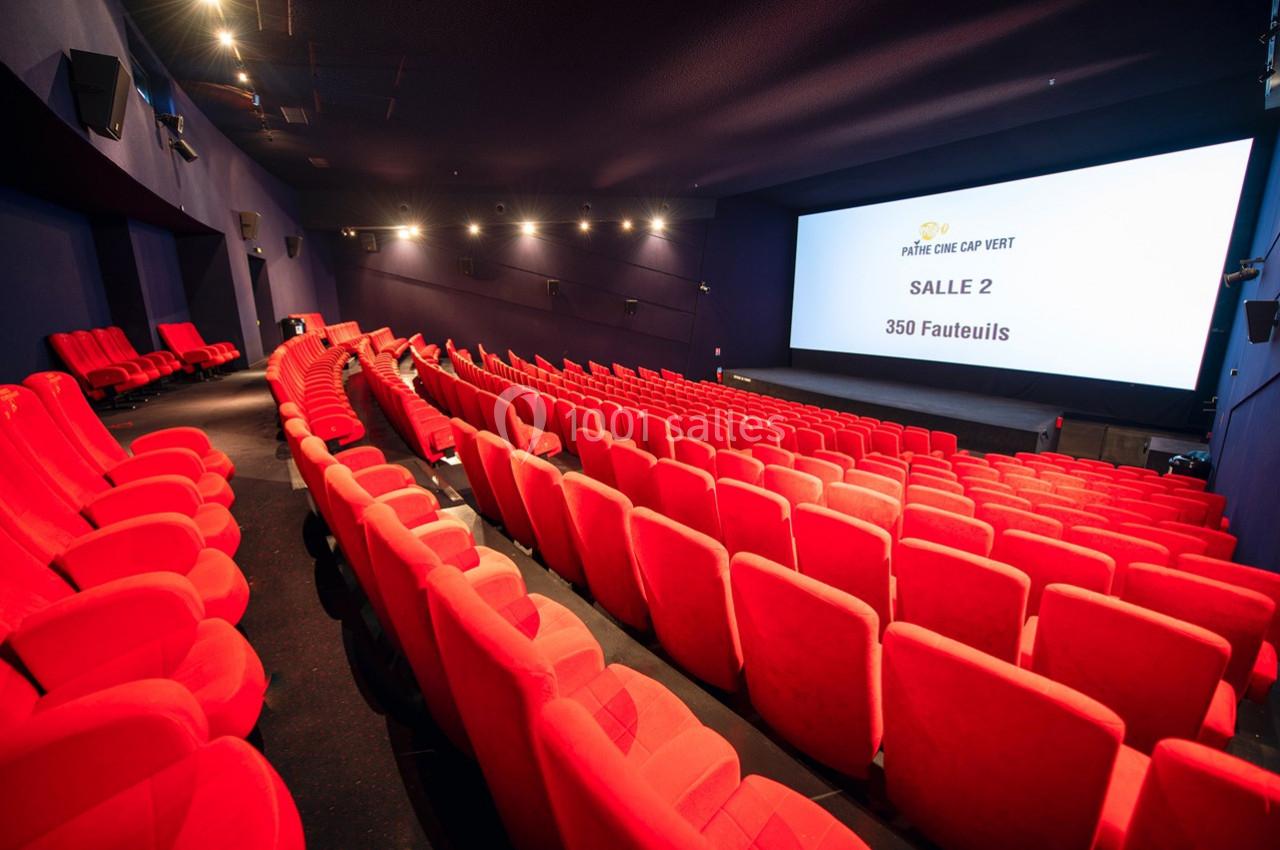 Salle de cinéma avec des rangées de fauteuils rouges vides, écran affichant ’Salle 2 - 350 fauteuils’.