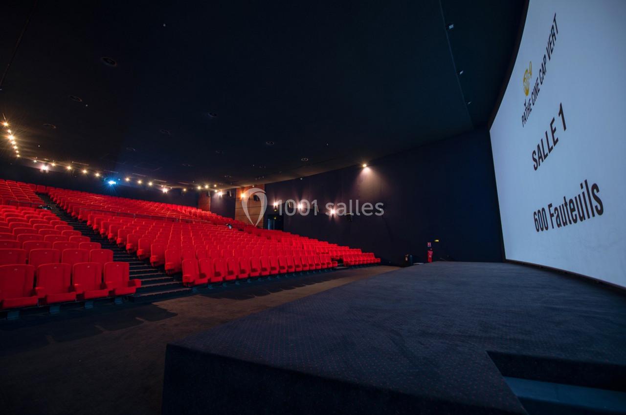Salle de cinéma vide avec des rangées de fauteuils rouges et un écran affichant ’Salle 1, 600 fauteuils’.