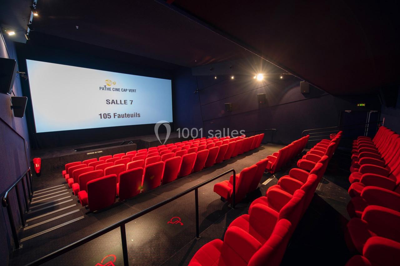 Salle de cinéma vide avec des rangées de fauteuils rouges et un écran affichant ’Salle 7 - 105 fauteuils’.