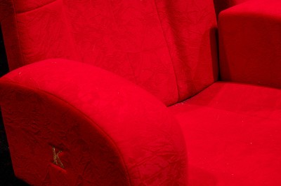 Rangée de fauteuils de cinéma rouges alignés dans une salle sombre.
