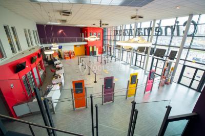 Salle de cinéma vide avec des rangées de sièges rouges et un grand écran allumé affichant un logo et du texte.
