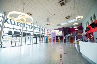 Salle de cinéma vide avec des rangées de sièges rouges et un grand écran allumé affichant un logo et du texte.