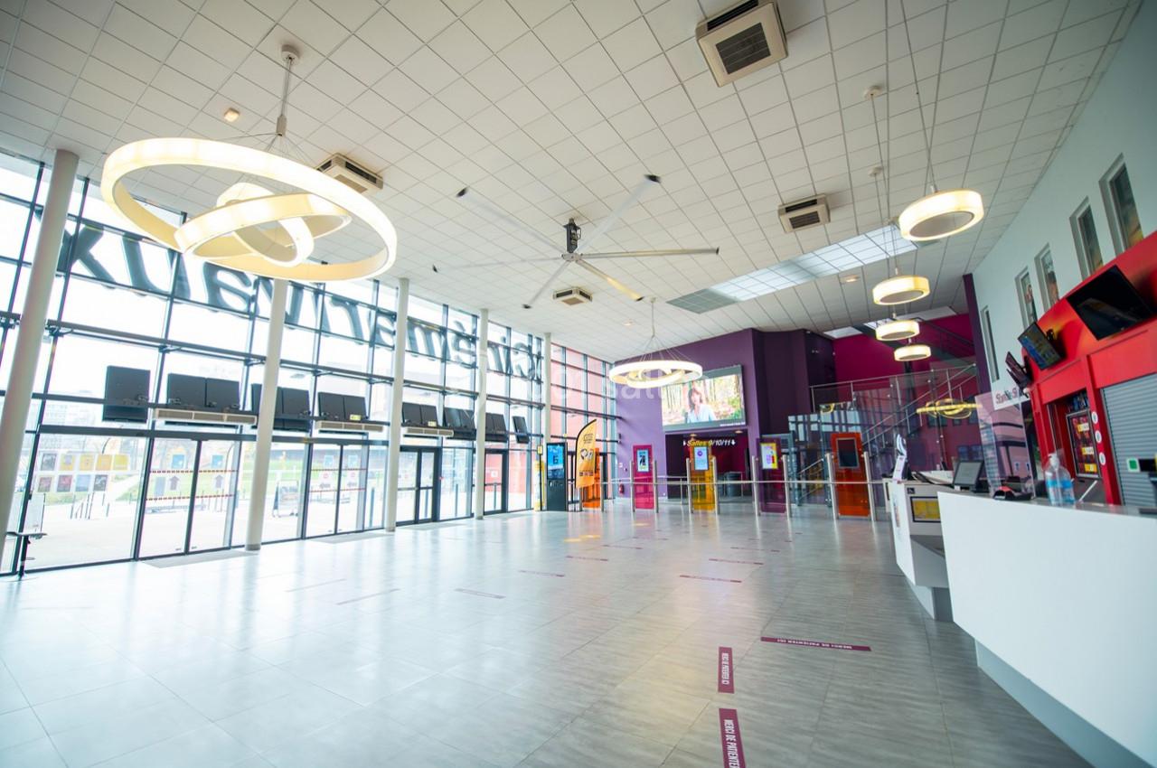 Hall spacieux et lumineux avec des baies vitrées, des guichets, des bornes interactives et un comptoir d'accueil.