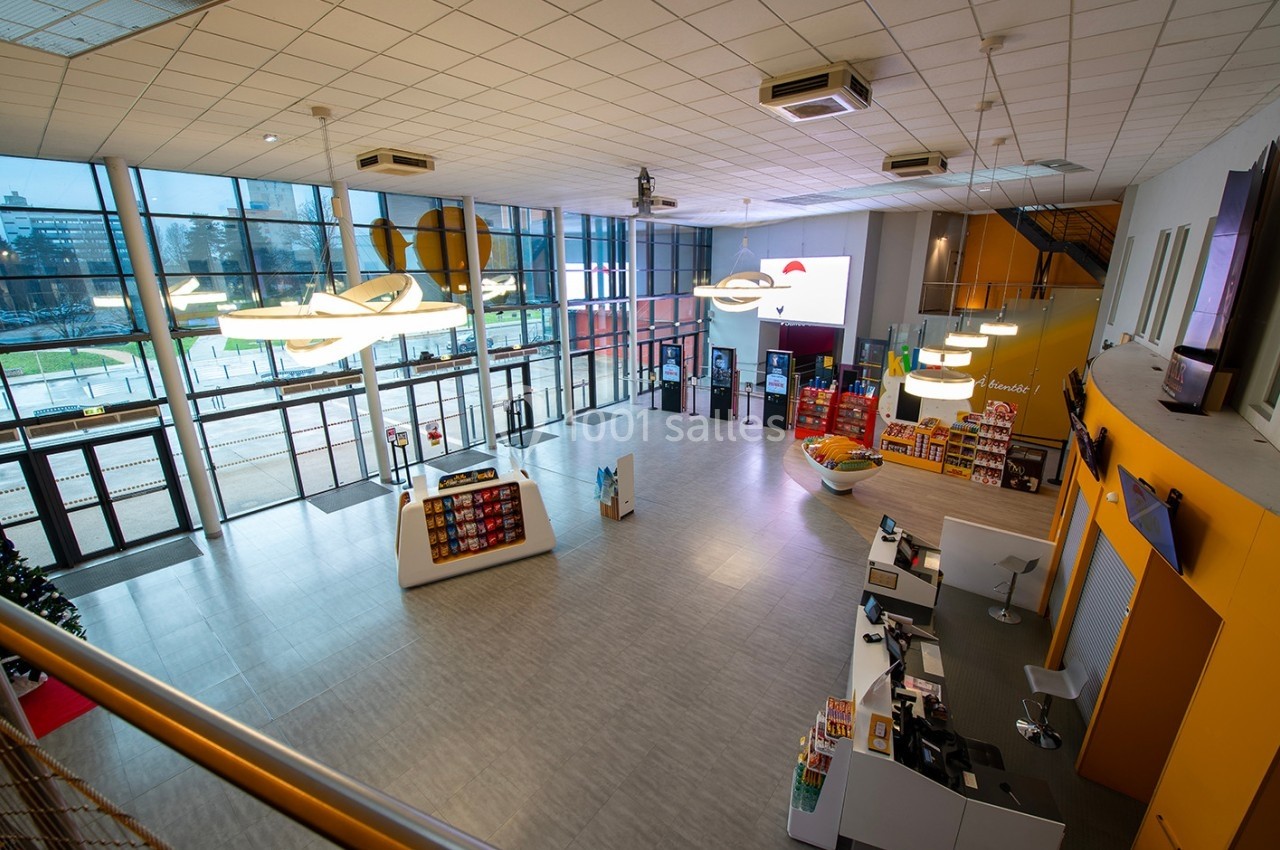 Vue d'un hall spacieux avec comptoir d'accueil, étagères de produits et grandes baies vitrées donnant sur l'extérieur.