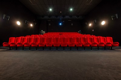 Une personne sert un verre de jus d'orange sur une table garnie de carafes, verres et viennoiseries.