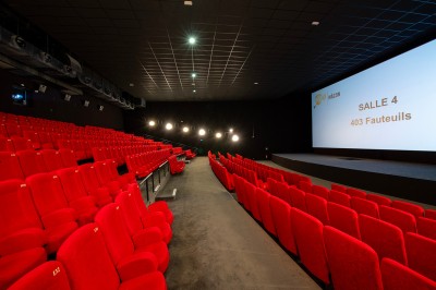 Une personne sert un verre de jus d'orange sur une table garnie de carafes, verres et viennoiseries.